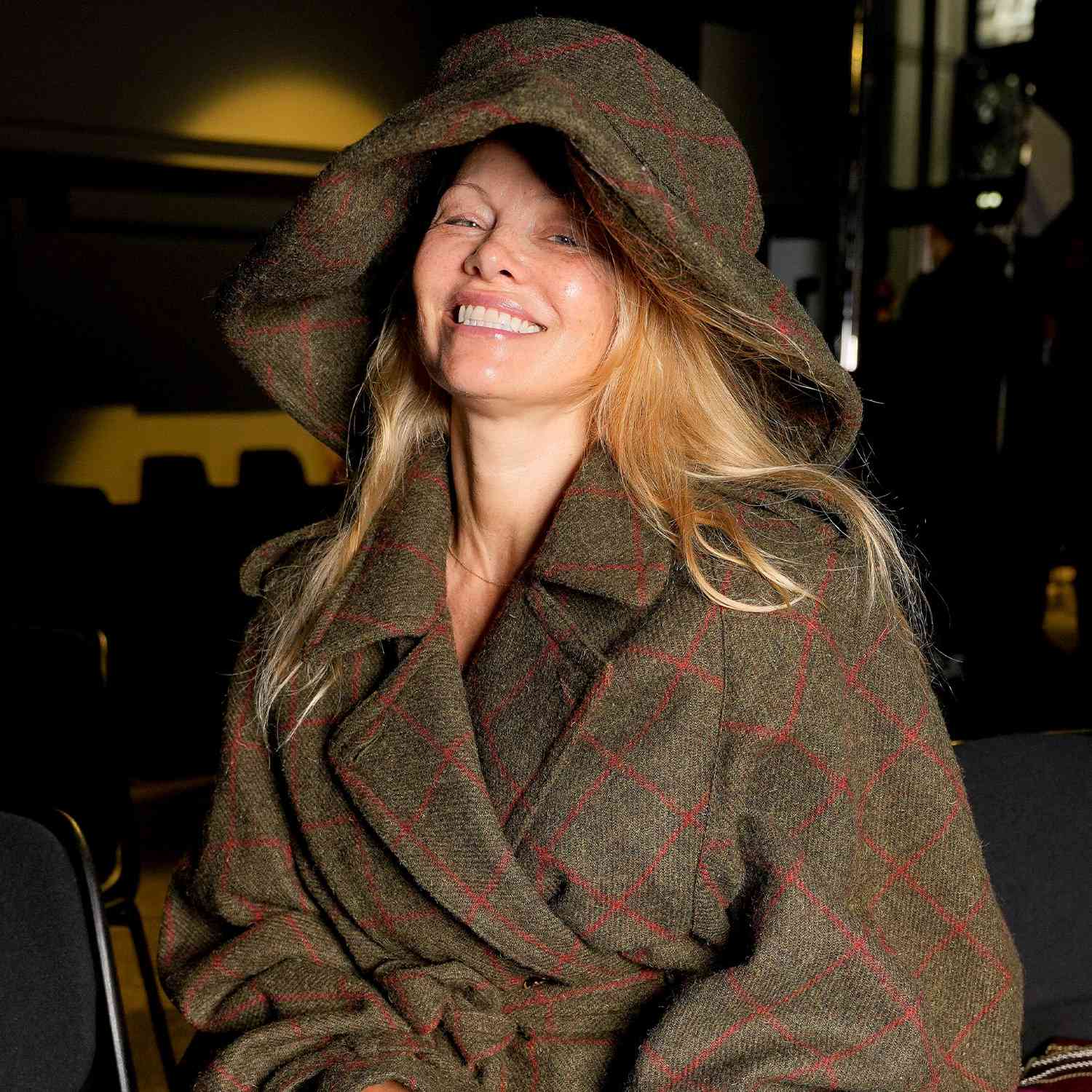 Pamela Anderson at the Vivienne Westwood show at Paris Fashion Week in no makeup and an oversized wool trench coat