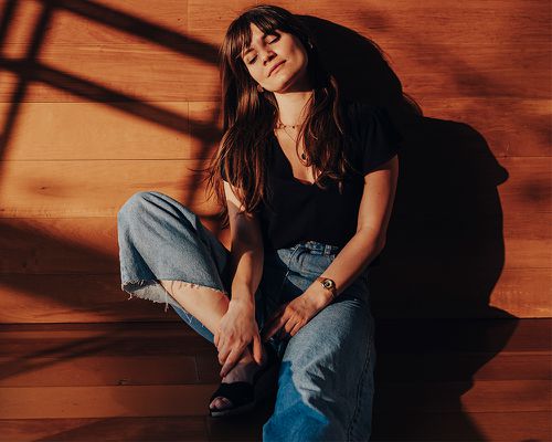 Woman Enjoying The Sunlight With her Eyes Closed While Sitting on the Wooden Floor