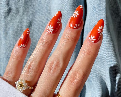 An orange manicure with a retro daisy design