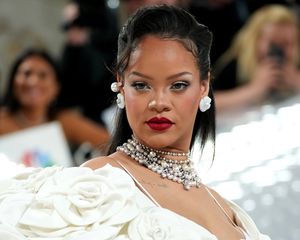 Rihanna at the met gala with an all white outfit and red lipsticks