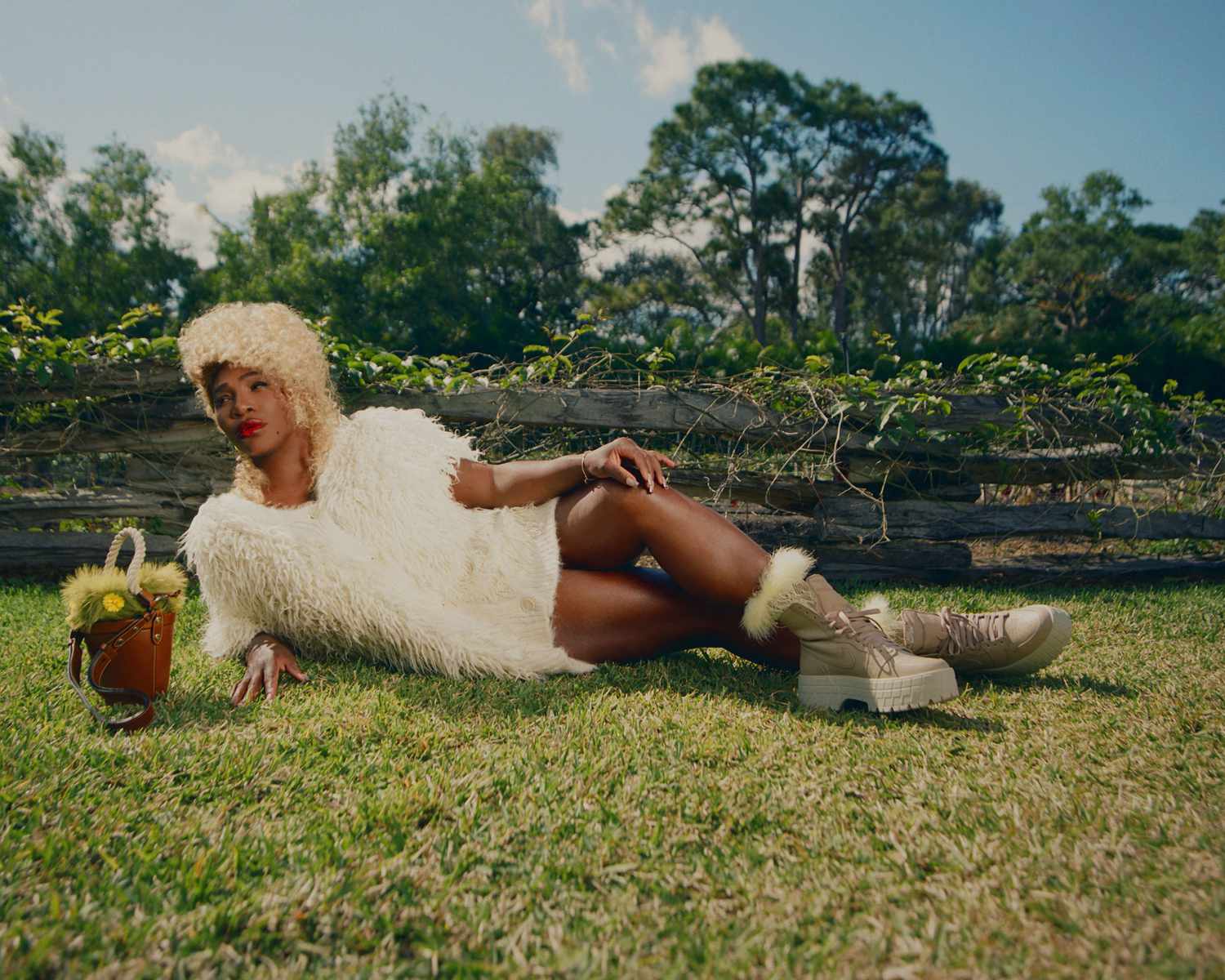 Serena Williams White Fluffy sweater blonde curly hair lying down on the grass