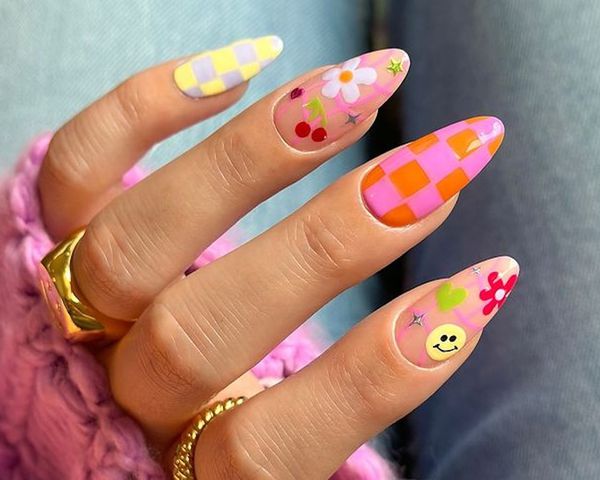 Manicure with colorful checkerboard design and smiley, heart, floral, cherry, and sparkle accents