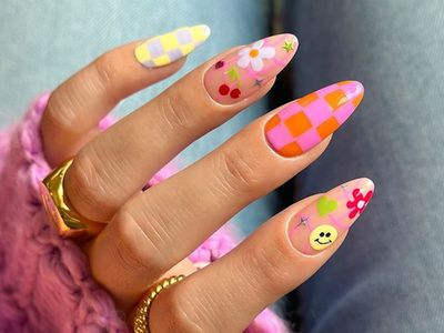 Manicure with colorful checkerboard design and smiley, heart, floral, cherry, and sparkle accents