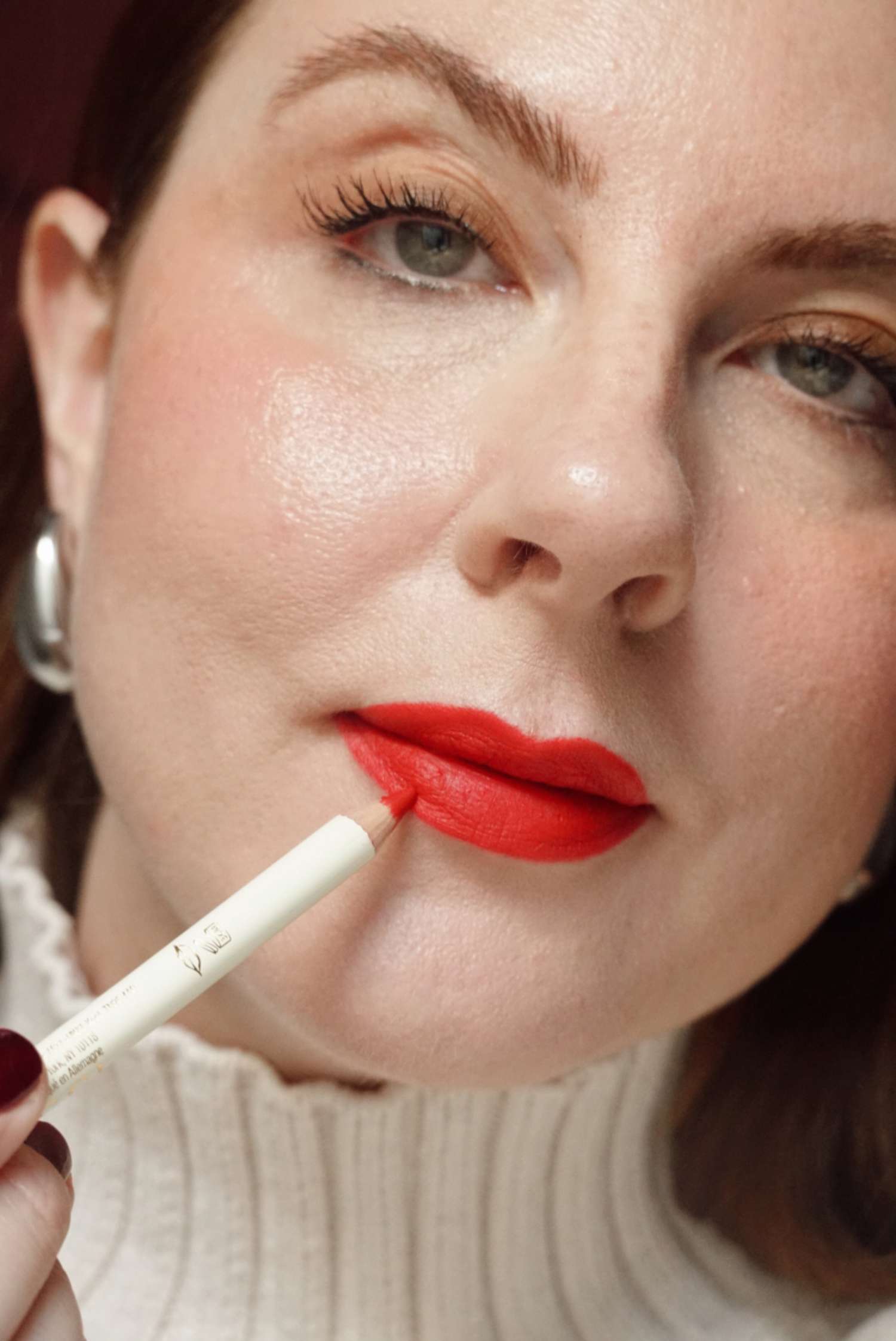 woman applying red lip liner to red lips