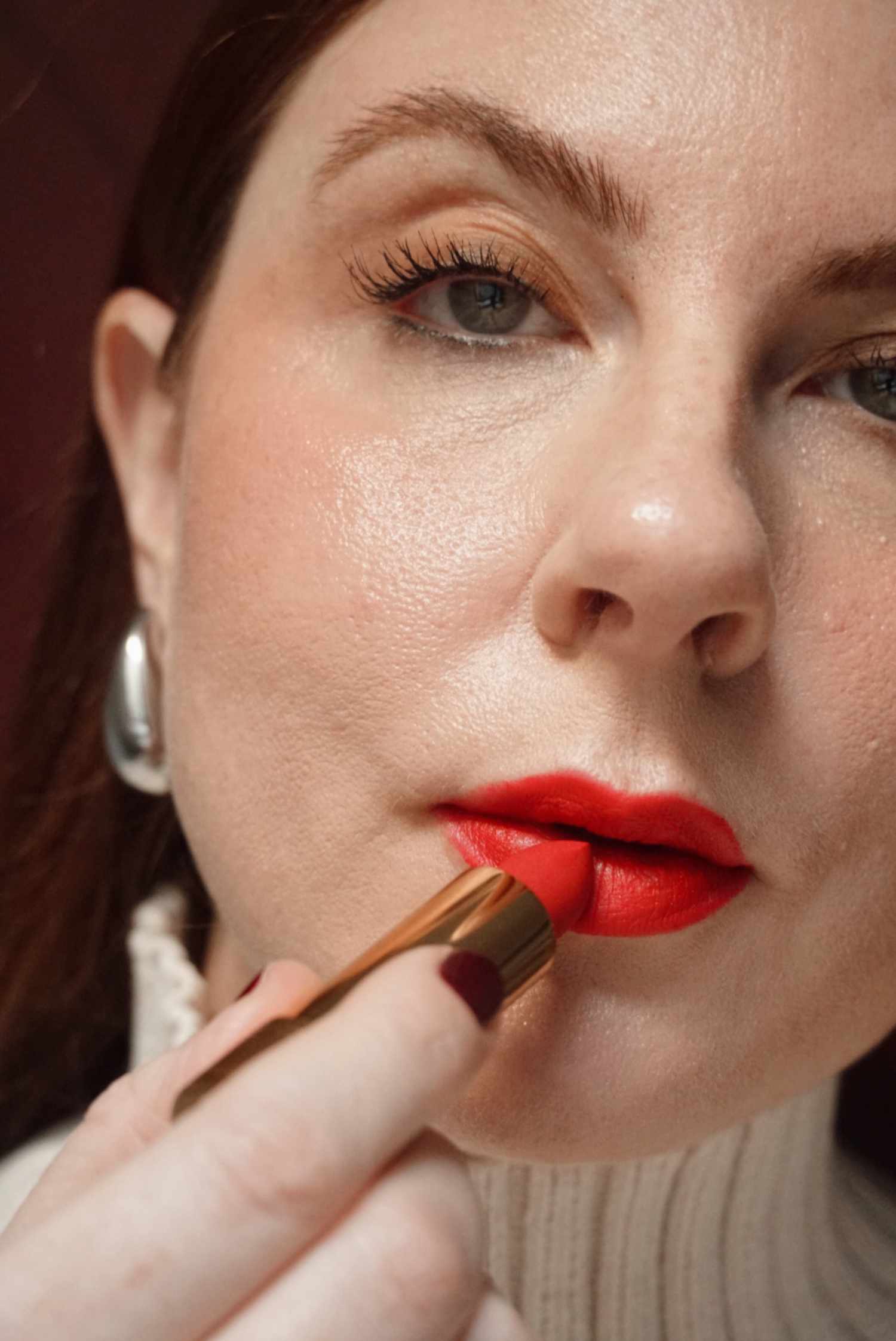 woman applying red lipstick from the tube to the bottom center of the lip