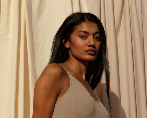 Woman with glowing skin standing in front of curtain background