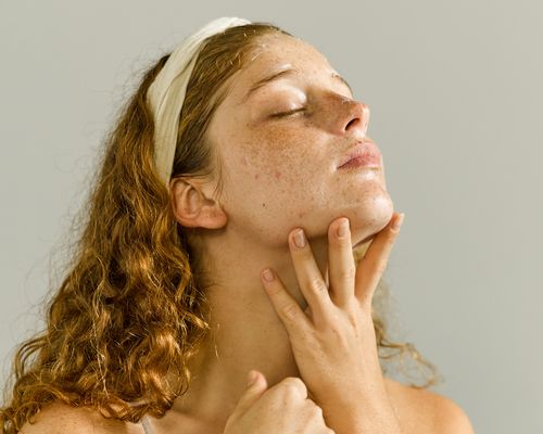 Woman massaging her chin and neck while wearing a headband