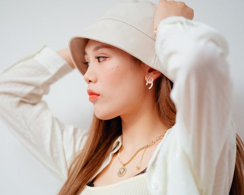 Woman wearing a bucket hat, hands on her head