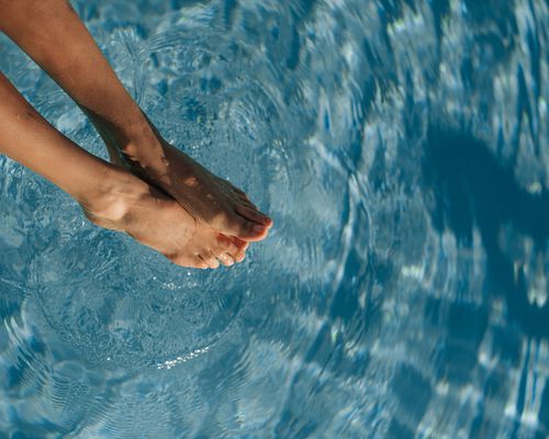 woman soaking feet in pool