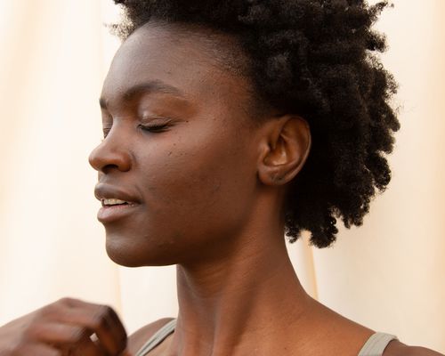 woman with acne under cheeks against cream background