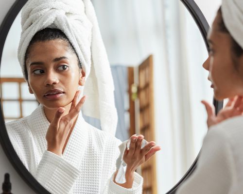 woman applying skincare in the mirror