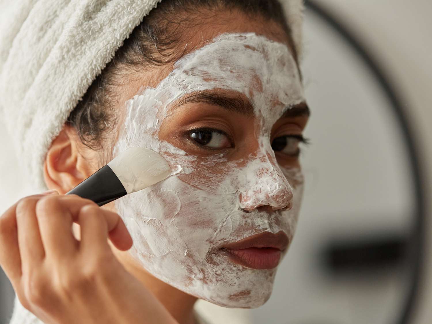 Woman applying face mask treatment with brush