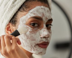 Woman applying face mask treatment with brush