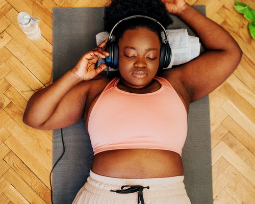 black femme lying on mat after workout