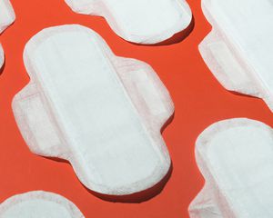 Several clean white menstrual pads on orange background