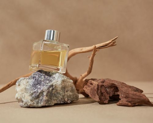 Bottle of perfume oil with rock, stick, and piece of wood