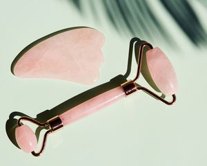 Rose quartz gua sha tools on a green background