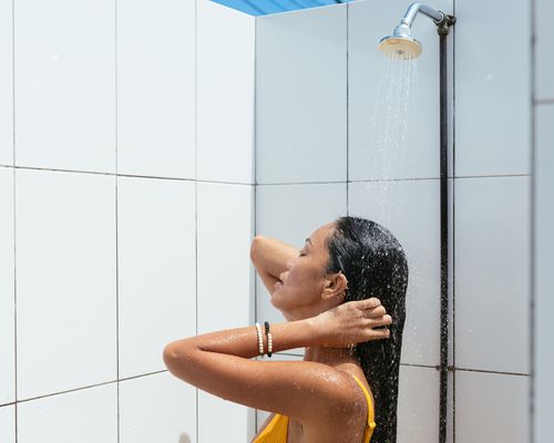 woman taking outdoor shower in bathing suit