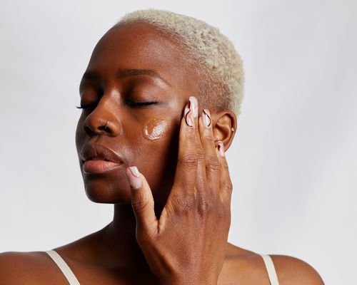 woman applying moisturizer to face