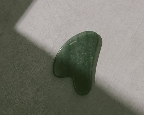 green gua sha stone on gray background