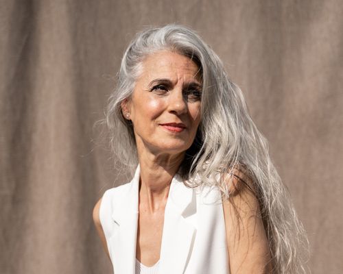 woman with silver hair posing against gray backdrop