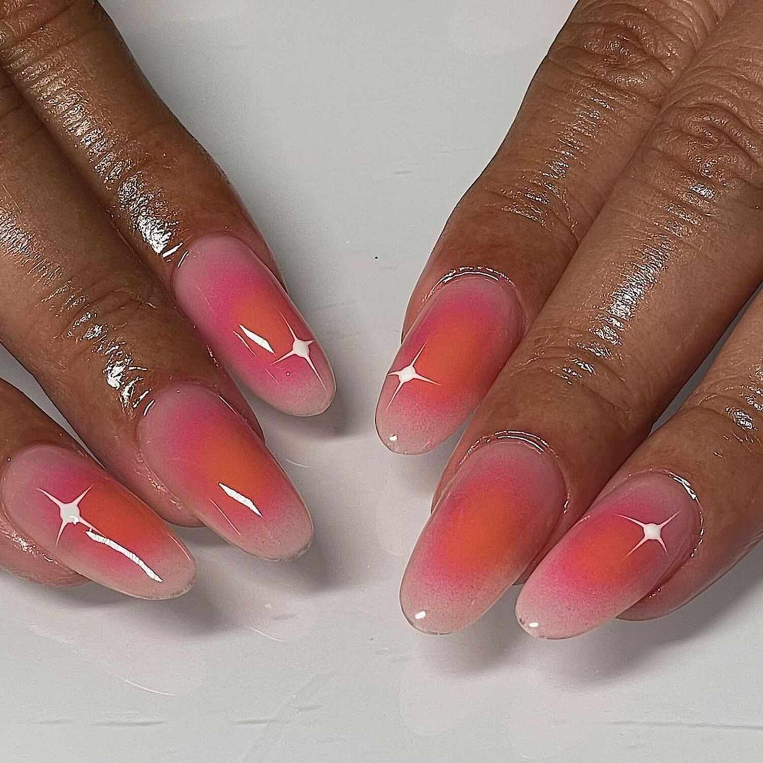 A baby pink manicure with orange airbrush details