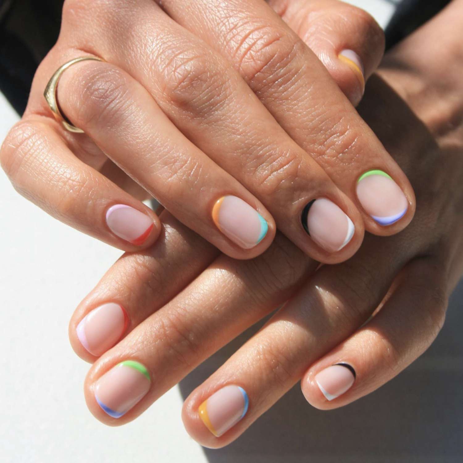 pale pink nails trimmed in the colors of the rainbow