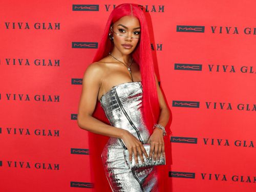 Teyana Taylor posing with long red hair in a silver dress with face jewelry and silver clutch