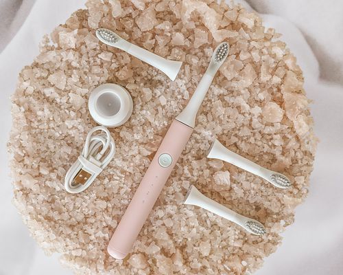 Electric toothbrush surrounded by different replacement parts