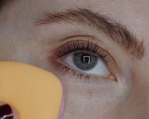 Close up of a woman adding setting powder to her under-eye area