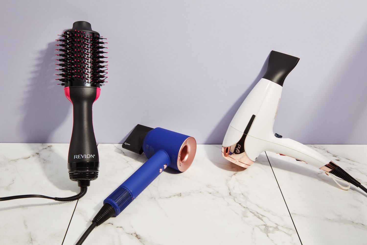 A side-by-side selection of blow dryers for fine hair displayed on a marbled surface