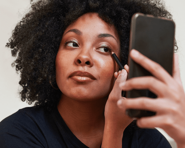 Close up of a woman applying pencil eyeliner.