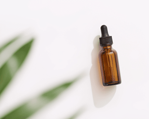 Image of a brown glass dropper bottle and leaves in the corner