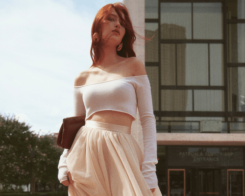 Woman with red hair wearing off the shoulder cropped pink top 