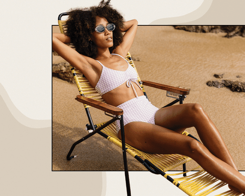 BIPOC Woman Lounging in a Beach Chair Wearing Sunglasses and A Lavender Gingham Retro Inspired Bikini 