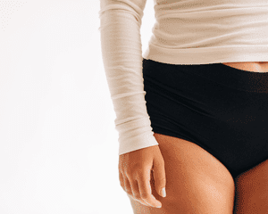 Image of a woman's torso in a long sleeve shirt and black brief underwear