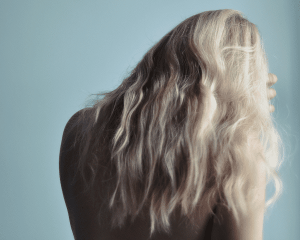 The back of a woman with bleach blonde hair flowing down her back