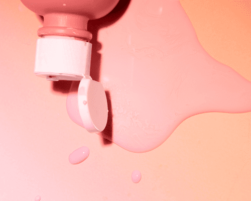 Close up of pink calamine lotion spilled on to an orange background.