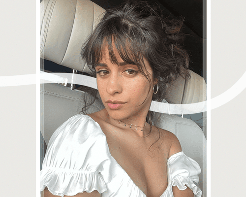 camila cabello in white off the shoulder top with fringe bangs and updo