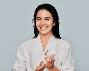 Image of a woman in a robe holding a jar of moisturizer