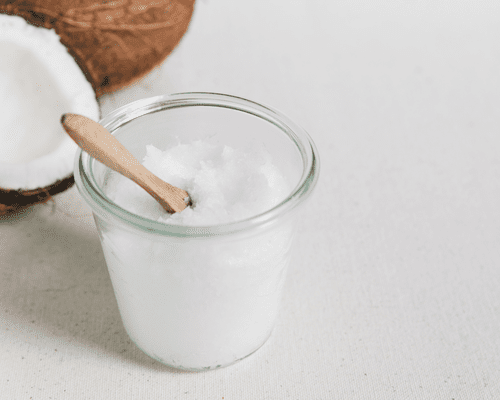 Close up of a coconut and a jar with solid coconut oil