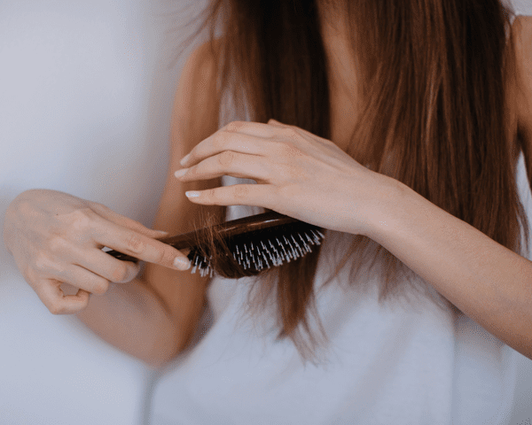 A woman holding a hair brush and brushing the ends of her hair