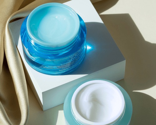  Two blue jars of facial cream.