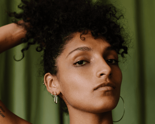 woman running hands through curly hair against green background