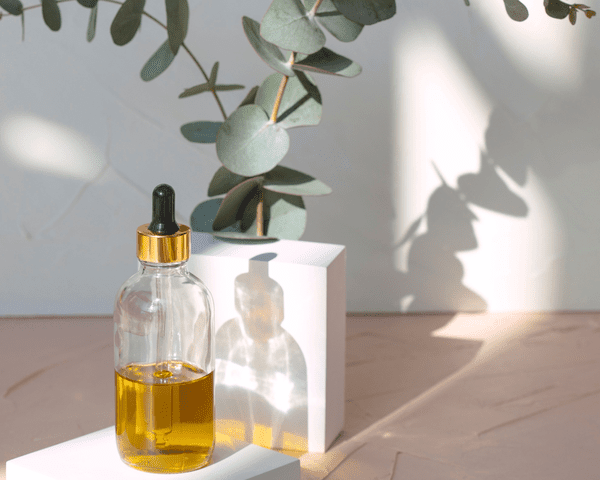 hair oil in bottle with dropper and eucalyptus plants