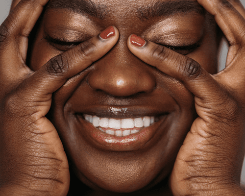 Close up of a smiling woman with her fingers framing her eyes