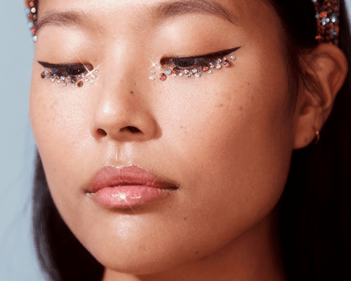 A woman with winged eyeliner on top and gems lining her lower lash line