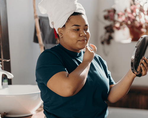 Close up of woman looking at her face in handheld mirror