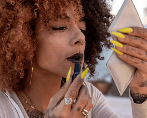 Close up of a woman applying a dark fall lipstick 