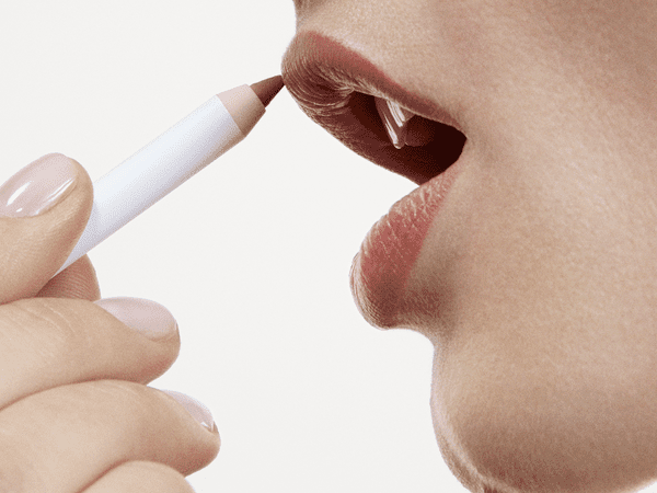A woman applying the Glossier Lip Line Enhancing Pencil
